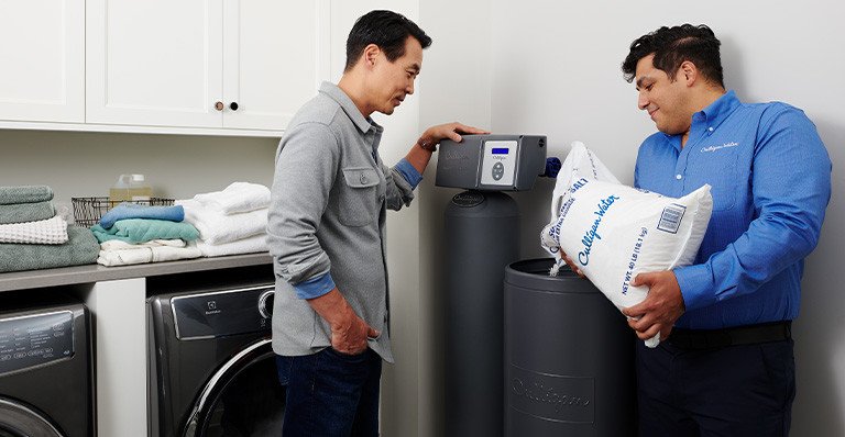 Culligan man fills water softener tank with salt as customer looks on